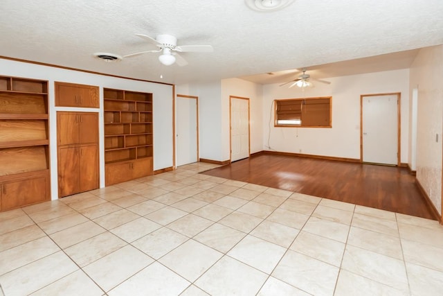 interior space featuring built in shelves, ceiling fan, and a textured ceiling