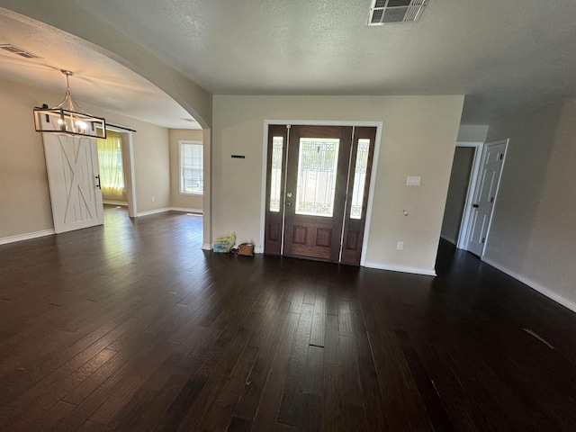 foyer featuring dark hardwood / wood-style flooring, a textured ceiling, and an inviting chandelier