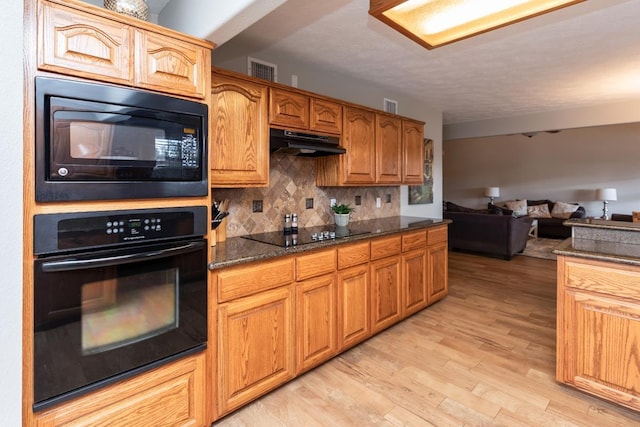 915 S 23rd St, Nederland, TX 77627 - kitchen featuring light wood-type flooring, open floor plan, decorative backsplash, under cabinet range hood, and black appliances