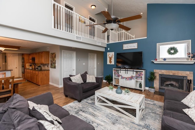 915 S 23rd St, Nederland, TX 77627 - living room featuring a fireplace with flush hearth, a towering ceiling, visible vents, baseboards, and ceiling fan with notable chandelier