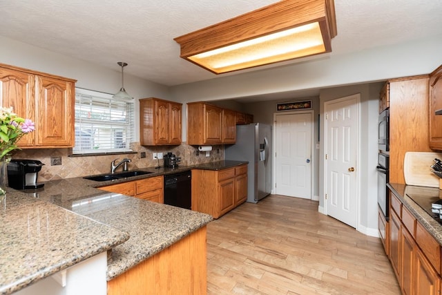 915 S 23rd St, Nederland, TX 77627 - kitchen with tasteful backsplash, a sink, brown cabinetry, black appliances, and light wood-type flooring