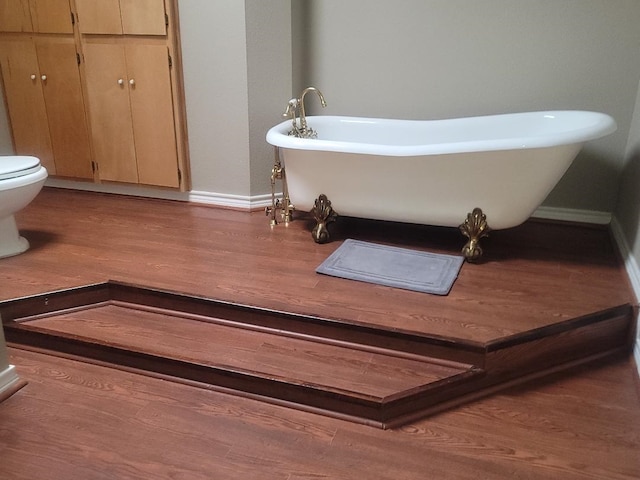 bathroom featuring a bathing tub, hardwood / wood-style floors, and toilet