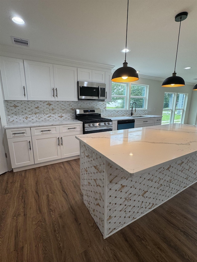 3128 58th St, Port Arthur, TX 77640 - kitchen with appliances with stainless steel finishes, dark wood finished floors, white cabinets, light stone countertops, and recessed lighting