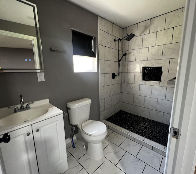 bathroom with tiled shower, vanity, and toilet