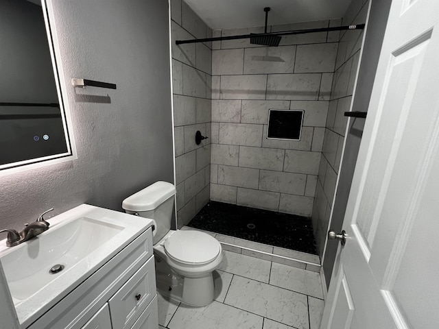 bathroom featuring a tile shower, vanity, and toilet