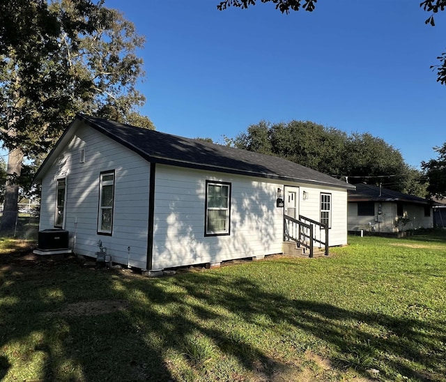 back of property featuring central AC unit and a lawn