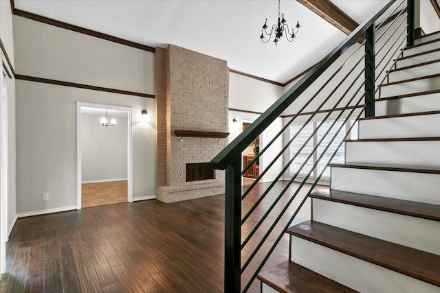 stairs featuring beamed ceiling, hardwood / wood-style floors, a large fireplace, and a notable chandelier