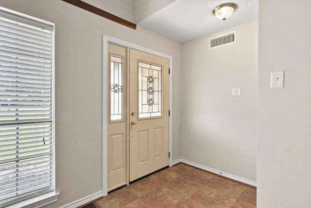 foyer entrance featuring a textured ceiling and light tile patterned flooring