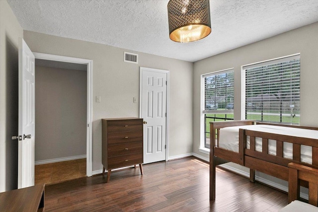 bedroom with a closet, dark wood-type flooring, and a textured ceiling