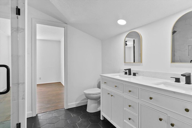 bathroom with tile patterned floors, vanity, a textured ceiling, toilet, and lofted ceiling