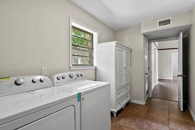 laundry area with independent washer and dryer, a textured ceiling, and dark tile patterned floors