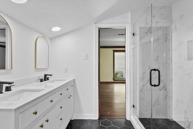 bathroom with tile patterned flooring, vanity, a textured ceiling, and walk in shower