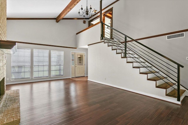 unfurnished living room featuring a fireplace, beam ceiling, hardwood / wood-style flooring, high vaulted ceiling, and a chandelier