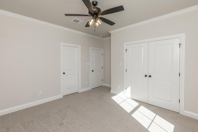 unfurnished bedroom with crown molding, light colored carpet, a closet, and ceiling fan