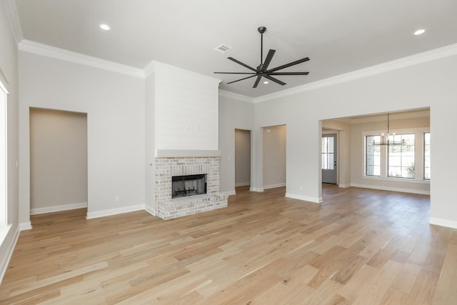 unfurnished living room with ornamental molding, a brick fireplace, ceiling fan with notable chandelier, and light hardwood / wood-style flooring