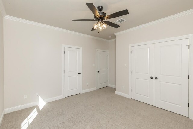 unfurnished bedroom with crown molding, light colored carpet, ceiling fan, and a closet