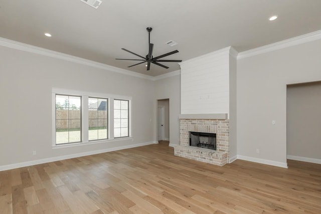 unfurnished living room with crown molding, ceiling fan, a brick fireplace, and light wood-type flooring