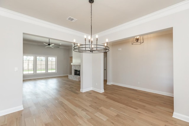 unfurnished living room with a brick fireplace, crown molding, ceiling fan, and light wood-type flooring