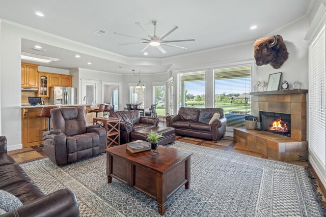 living room featuring crown molding, a fireplace, and ceiling fan