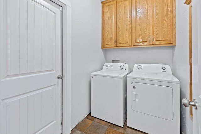 clothes washing area featuring washer and dryer and cabinets