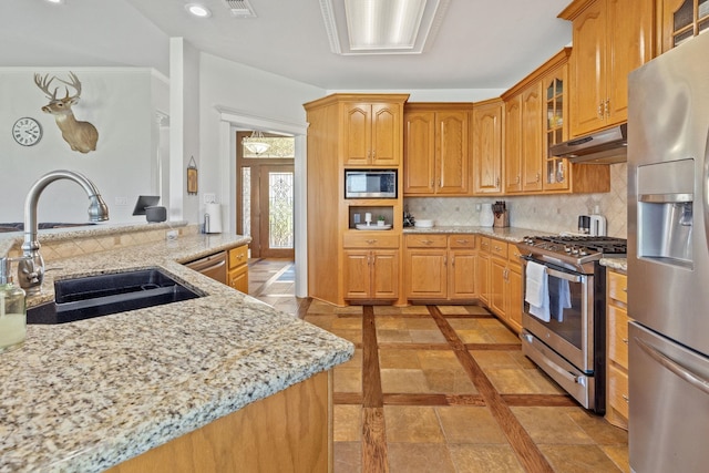 kitchen with tasteful backsplash, light stone countertops, sink, and stainless steel appliances