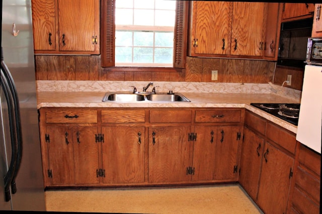 kitchen featuring decorative backsplash, black gas cooktop, sink, and stainless steel refrigerator