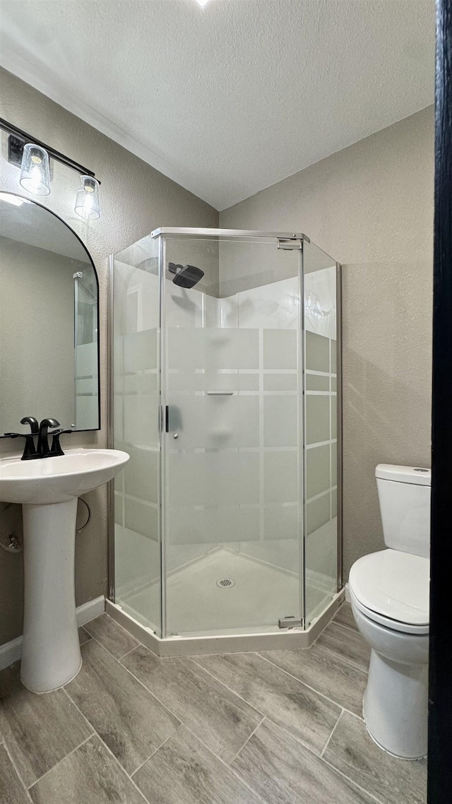 674 Ridgewood Dr, Port Neches, TX 77651 - bathroom featuring wood tiled floors, a textured ceiling, a stall shower, and toilet