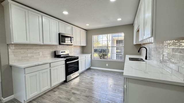 674 Ridgewood Dr, Port Neches, TX 77651 - kitchen with stainless steel appliances, a sink, baseboards, recessed lighting, and white cabinetry