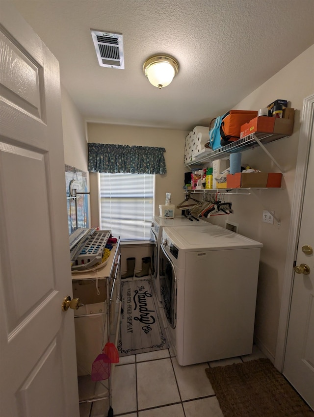 6220 32nd St, Groves, TX 77619 - laundry room featuring washing machine and clothes dryer, light tile patterned flooring, and a textured ceiling