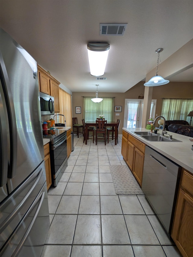 6220 32nd St, Groves, TX 77619 - kitchen featuring stainless steel appliances, brown cabinetry, pendant lighting, light countertops, and light tile patterned floors