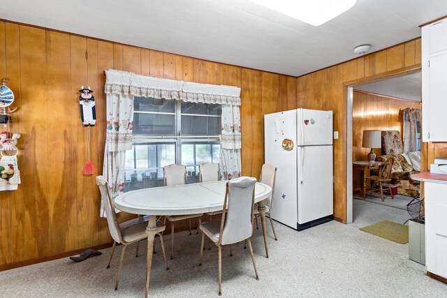 dining room with wooden walls and light carpet