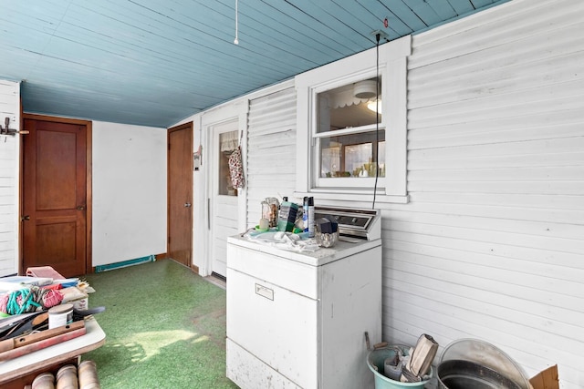 interior space with wooden walls, washer / clothes dryer, and dark colored carpet