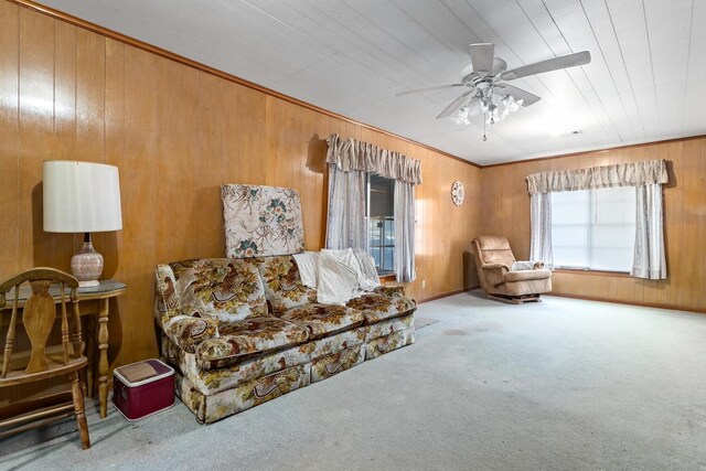 living area featuring carpet, ceiling fan, and wood walls