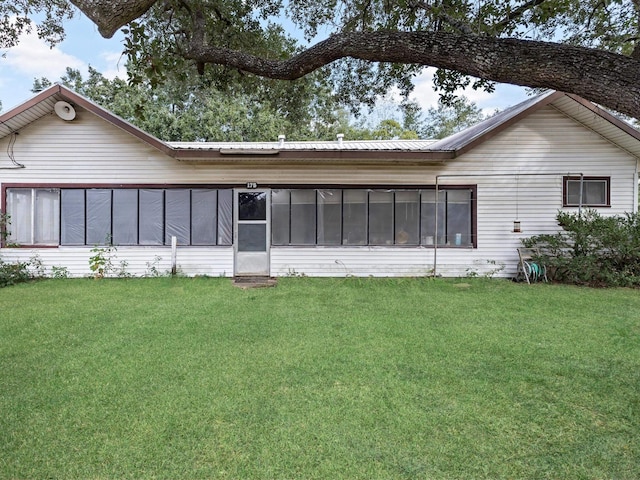 rear view of property featuring a lawn and a sunroom