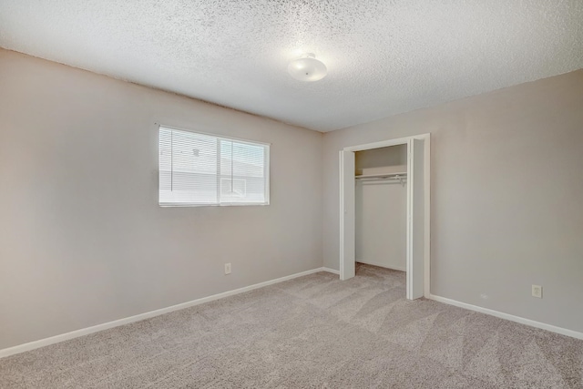 unfurnished bedroom featuring a textured ceiling, light colored carpet, and a closet