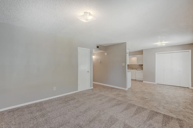 carpeted empty room featuring a textured ceiling