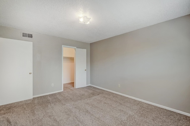 spare room with light carpet and a textured ceiling