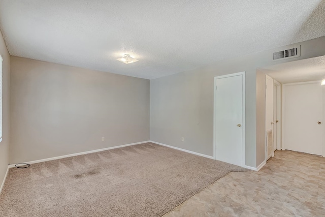 empty room featuring a textured ceiling and light colored carpet