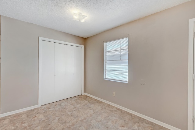 unfurnished bedroom featuring a textured ceiling and a closet