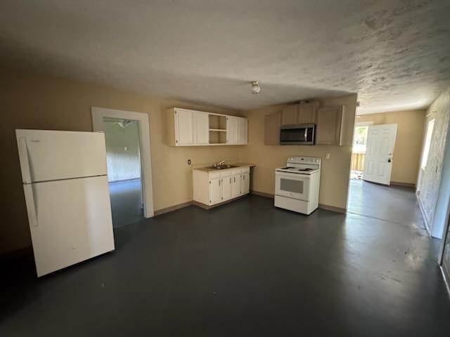 301 W Lavielle, Kirbyville, TX 75956 - kitchen featuring open shelves, a sink, white appliances, baseboards, and concrete floors