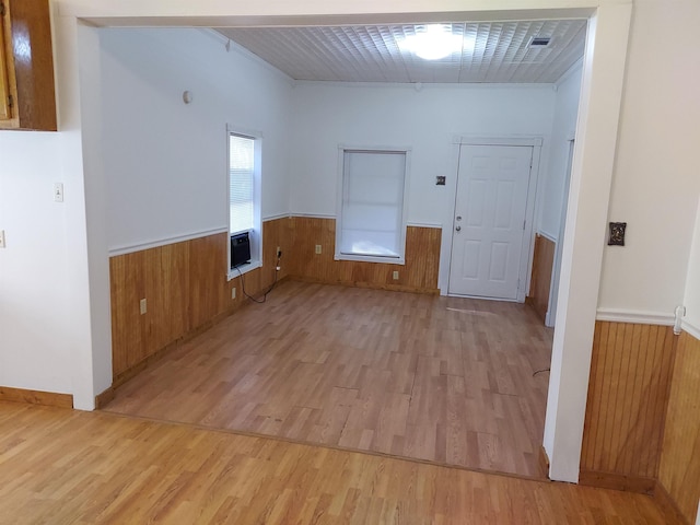 empty room with heating unit, wooden walls, and light hardwood / wood-style flooring