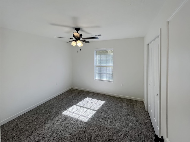 spare room featuring dark colored carpet and ceiling fan