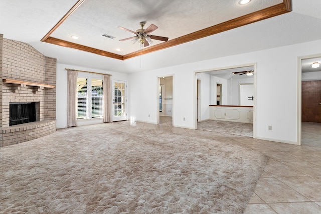 unfurnished living room featuring a ceiling fan, a tray ceiling, visible vents, and a fireplace