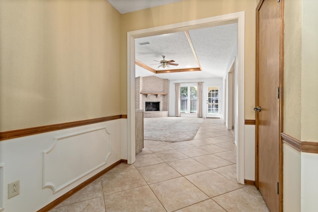hall featuring light tile patterned flooring, a raised ceiling, visible vents, and light carpet