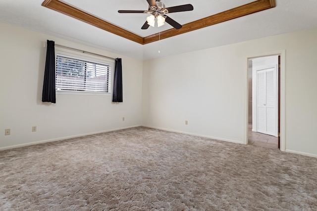 unfurnished room with ceiling fan, baseboards, carpet, and a raised ceiling