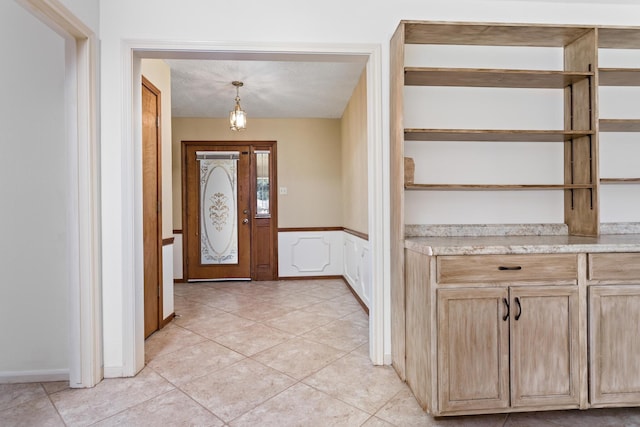 foyer entrance featuring a wainscoted wall and light tile patterned floors