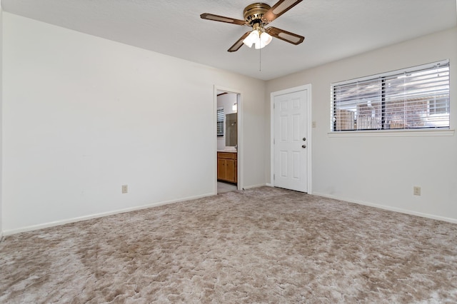 empty room with light colored carpet, baseboards, and a ceiling fan
