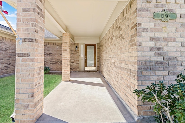 entrance to property featuring brick siding and a shingled roof