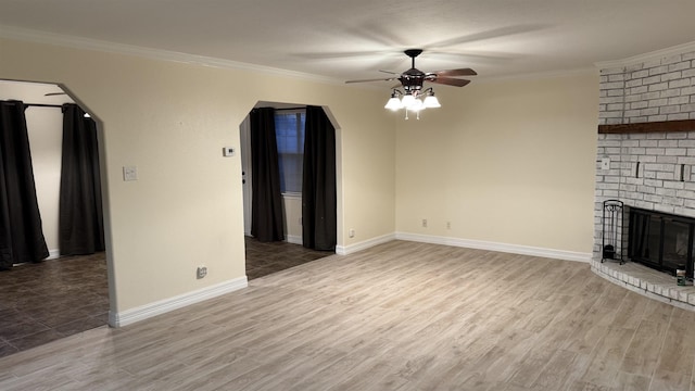 unfurnished living room featuring crown molding, ceiling fan, a fireplace, and hardwood / wood-style floors