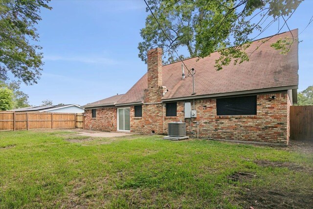 rear view of house featuring central AC unit, a patio area, and a lawn